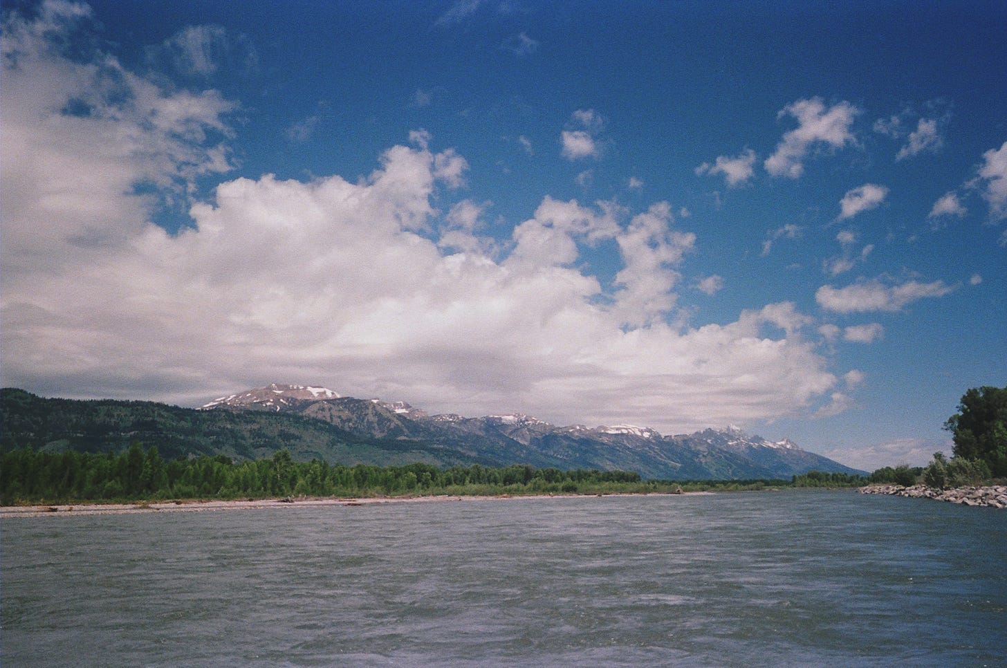 View of a lake with mountains on the horizon, overshadowed by big clouds