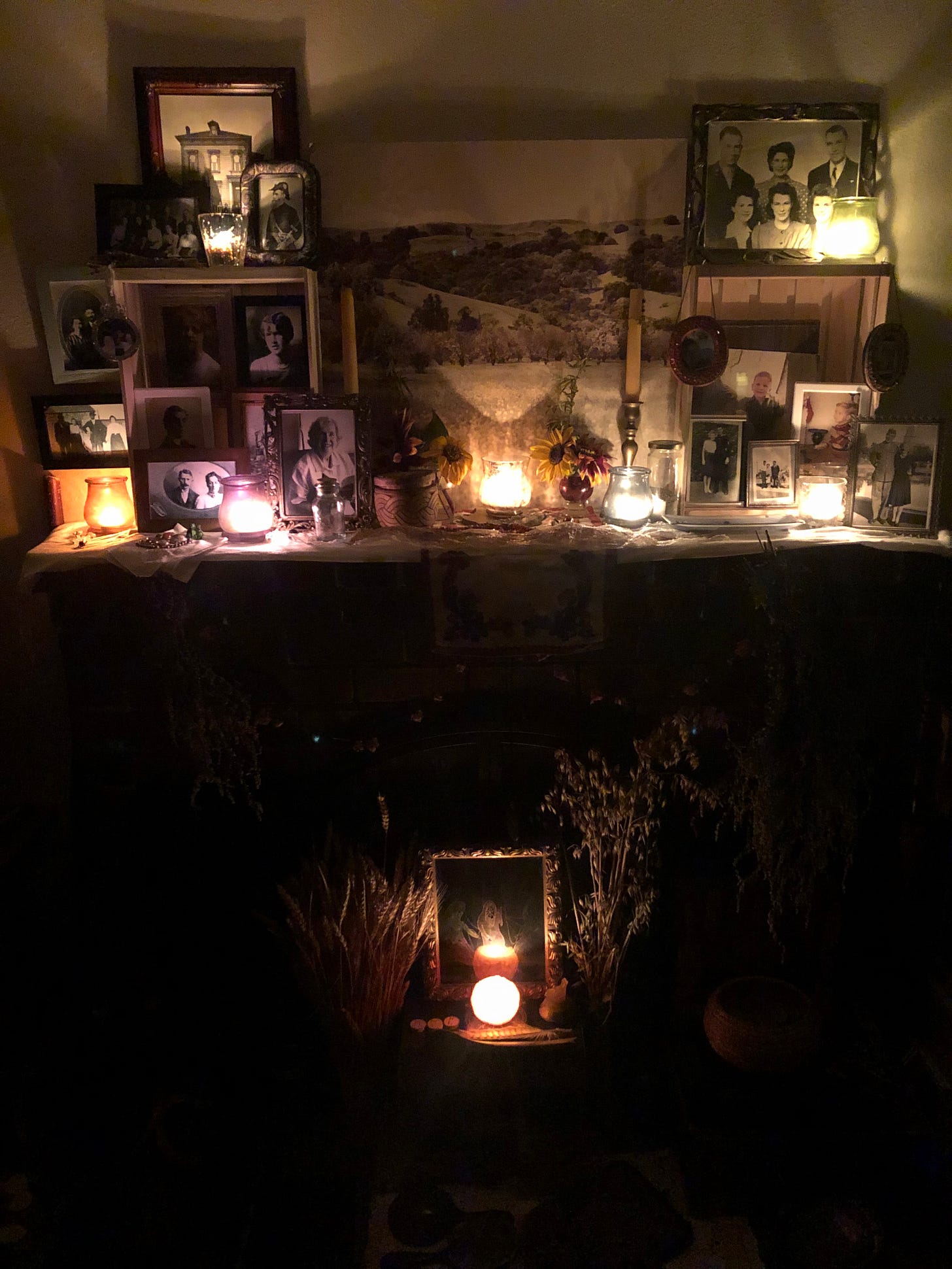 Ancestor altar with candles lit on my hearth featuring photos above and an image of the Norns below.