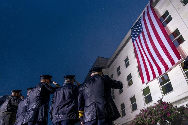 First responders salute in a driving rain as a U.S. flag is unfurled at the Pentagon in Washington, Sunday, Sept. 11, 2022, at sunrise on the morning of the 21st anniversary of the 9/11 terrorist attacks. (AP Photo/Andrew Harnik)