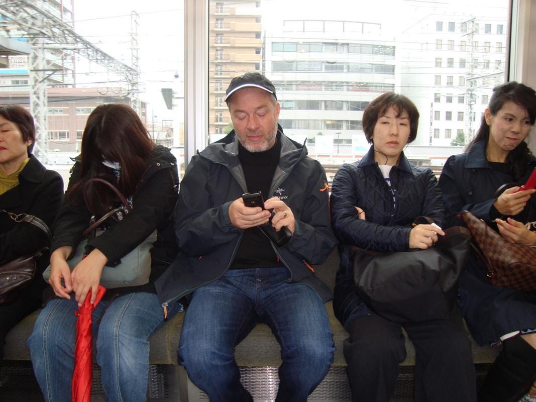 Train passengers on a train. One is using his mobile phone