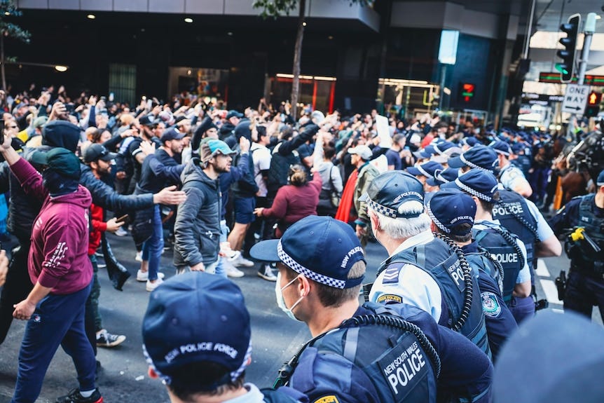 Angry people stand in front of police.