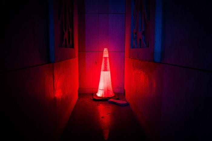 A traffic cone glowing red in the middle of a dark hallway