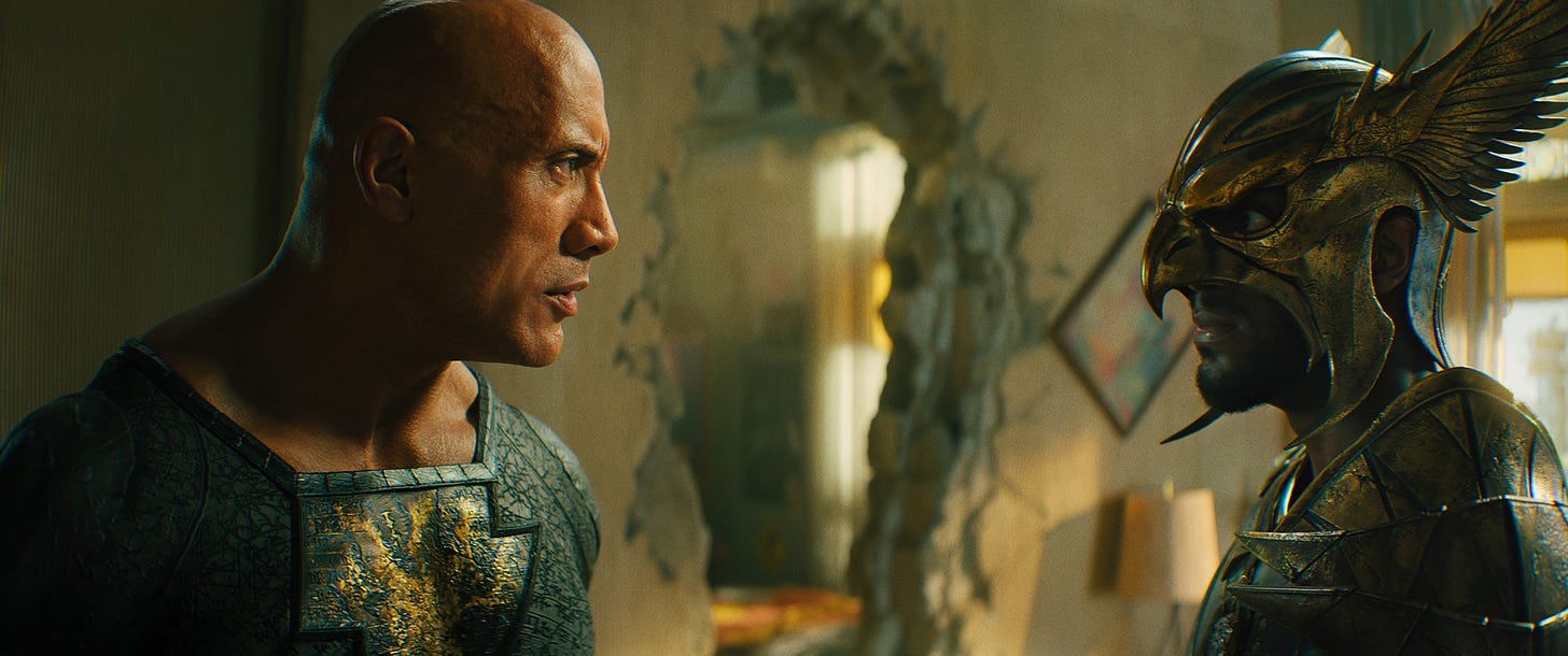 BLACK ADAM film still featuring Dwayne Johnson and Aldis Hodge staring at each other in a destroyed room.