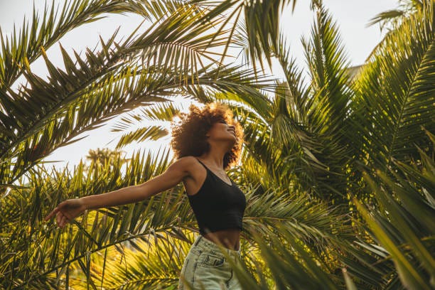 Pretty young afro woman among palm trees Pretty young afro woman among palm trees Travel stock pictures, royalty-free photos & images