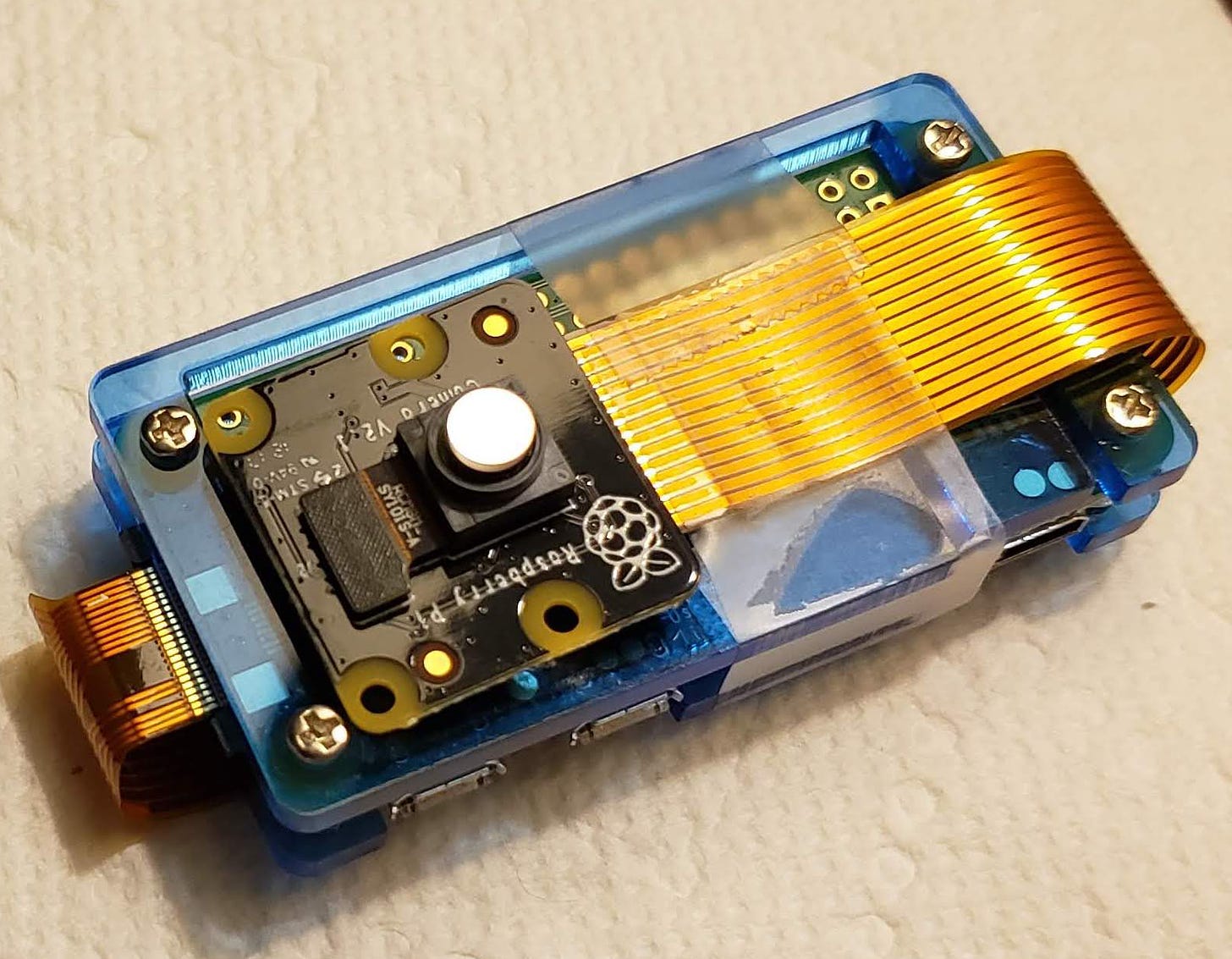 A small computer module, about the size of a thumb. It has a small camera attached. The lens of the camera is covered with what looks like s small round mirror.