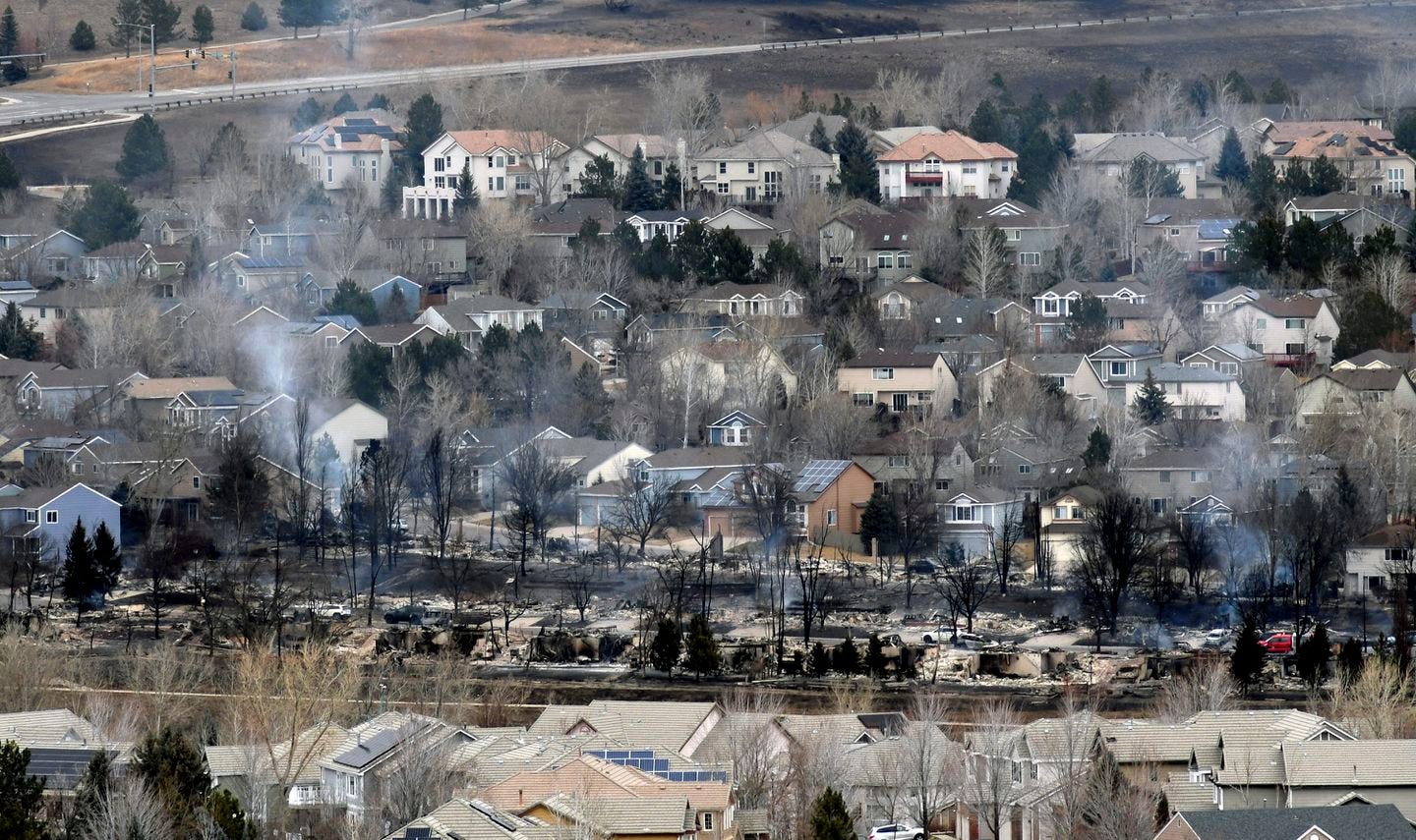 Smoke rose from the ashes of a neighborhood in Superior, Colo. on Friday, after a wind-whipped wildfire tore through the area the day before.