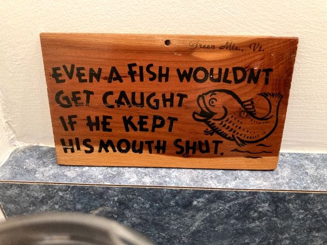 A wooden sign that reads "Even a fish wouldn't get caught if he kept his mouth shut"