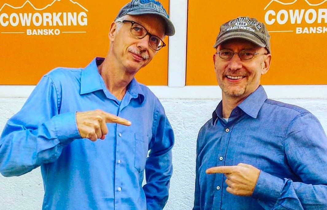 Brent and Michael pointing at each other because they are both wearing blue shirts and baseball caps. 