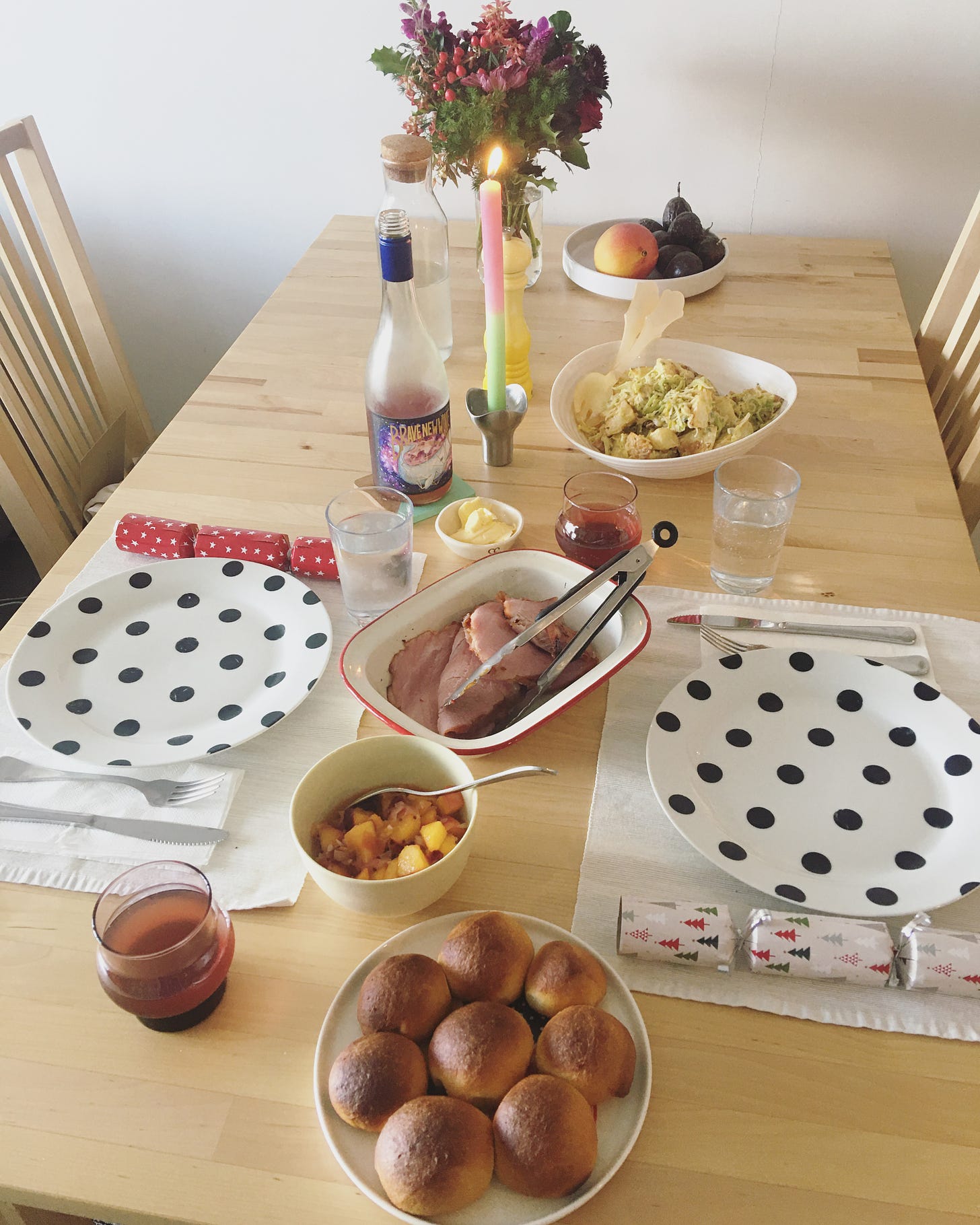 Dining table with Christmas lunch meal including potato salad, dinner rolls, ham and peach relish