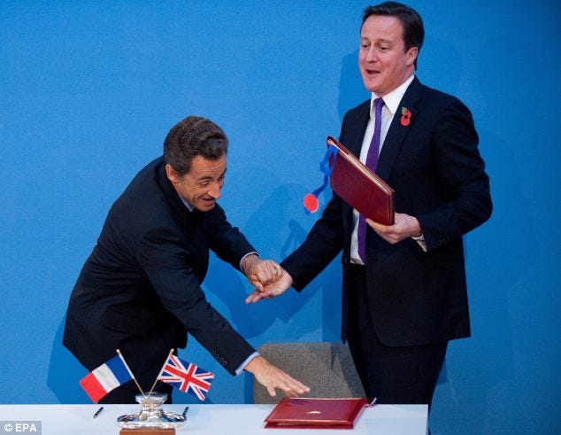 Helping hand: French President Nicolas Sarkozy and Prime Minister David Cameron joke after signing a treaty at an Anglo-French summit at Lancaster House in central London yesterday