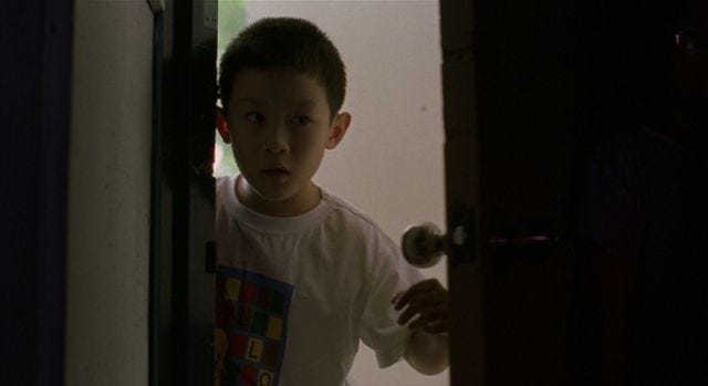 Small Chinese boy looks through an ajar door
