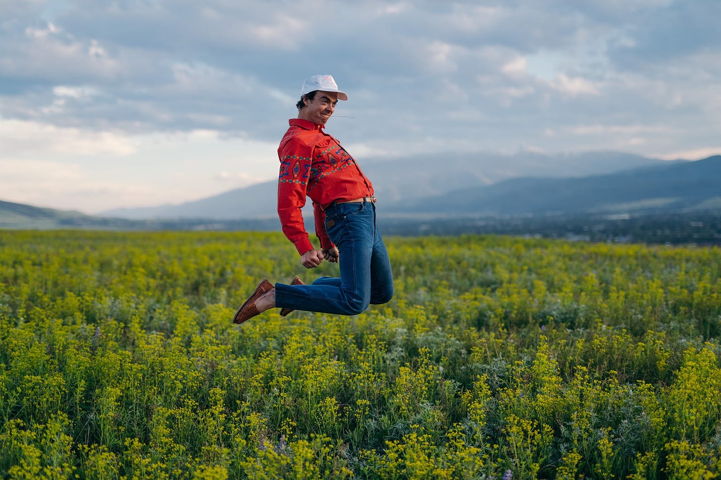 man in red jacket jumping in field