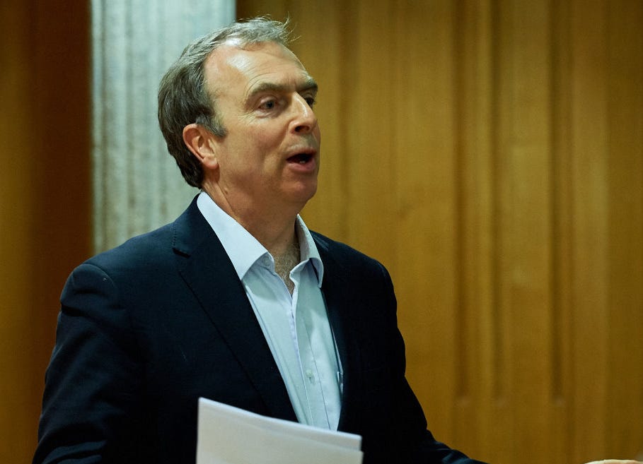 A graying man in a suit lecturing