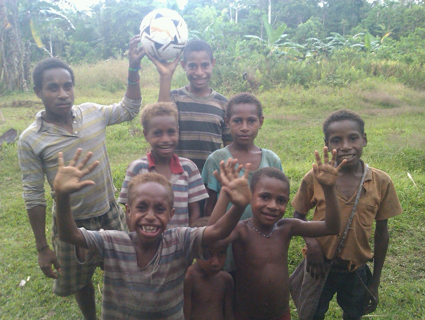 Kids posing happily with a soccer ball