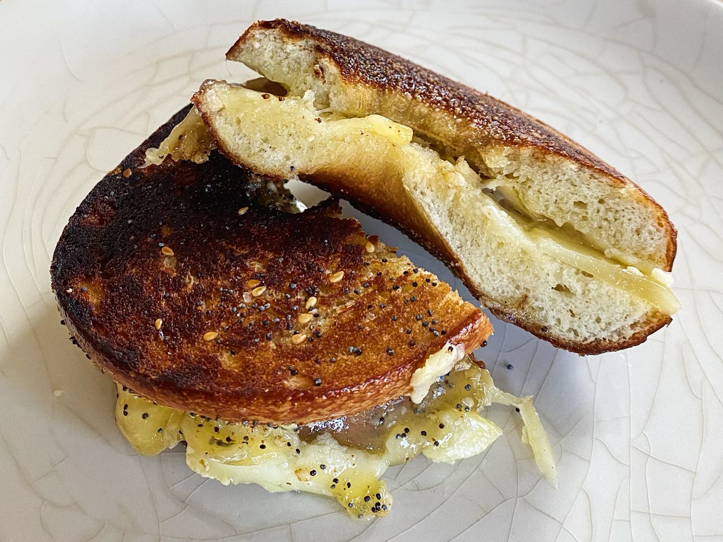 Two halves of bagel grilled-cheese sandwiches—one on an everything bagel, one plain