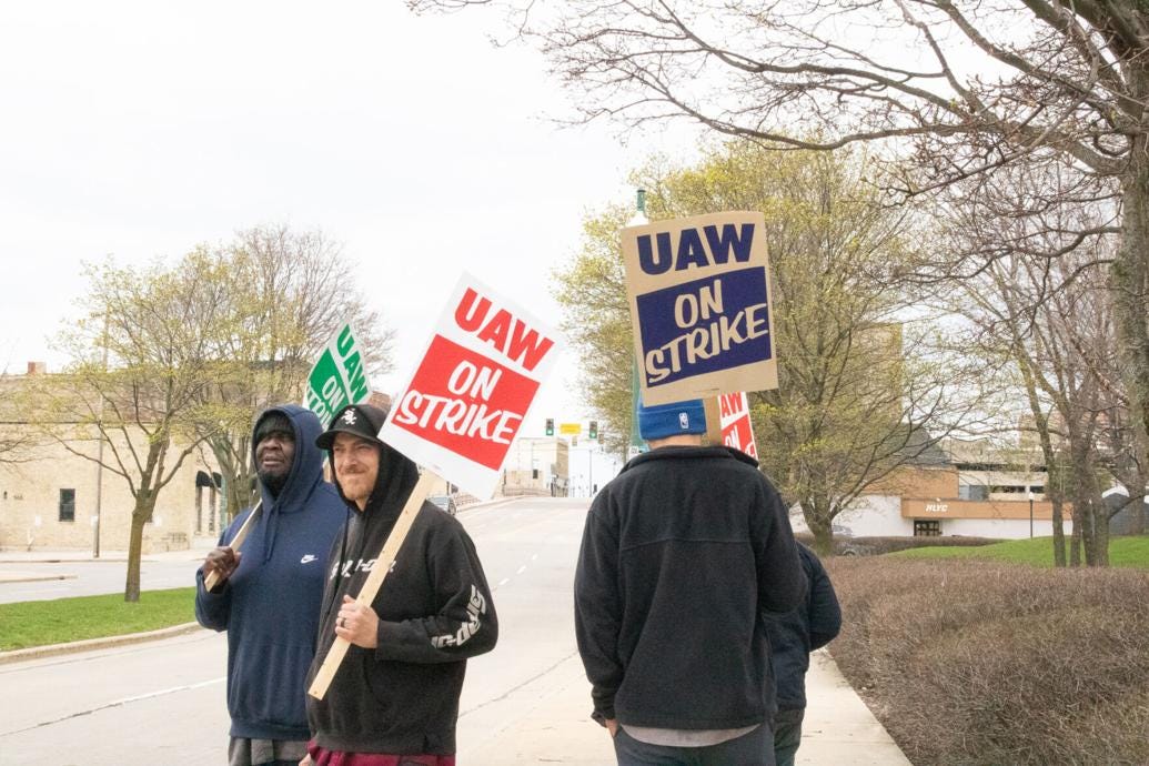 Photo from Racine Journal Times of two white male and one black male picketing UAW workers carrying signs that read "UAW On Strike" at the entrance to Case IH headquarters in downtown Racine.
