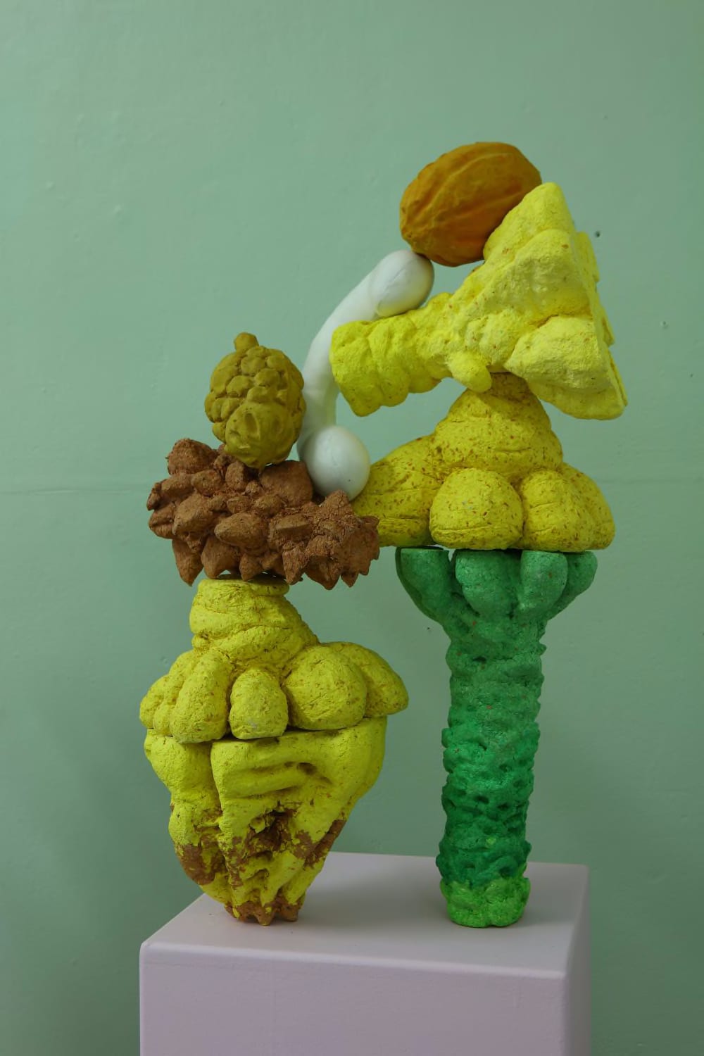 Two sculptural forms which are almost like figures. Lumpy and in yellow, green and brown they are organic-like materials stacked on top of each other.