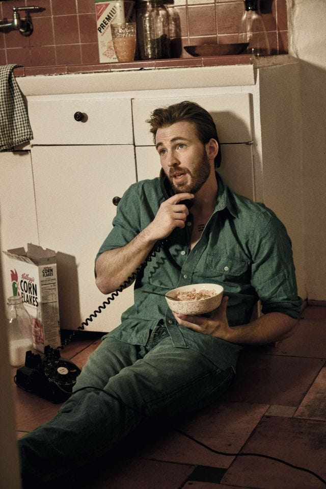 Chris Evans sitting on the floor in a green jumpsuit, with a phone in one hand and a bowl of cornflakes in the other. His sleeves are rolled up. Chris Evans sitting on the floor in a green jumpsuit, with a phone in one hand and a bowl of cornflakes in the other. His sleeves are rolled up.