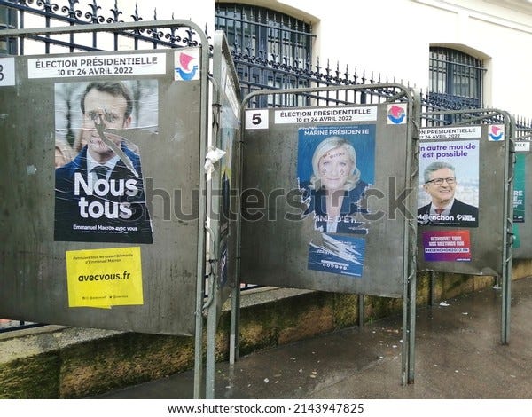 paris, france 8 avril 2022 : affiches électorales sur le panneau dans la rue. pour l'élection présidentielle française. affiches déchirées d'emmanuel macron, de marine le pen, de jean luc melenchon. jour de pluie. trottoirs humides.