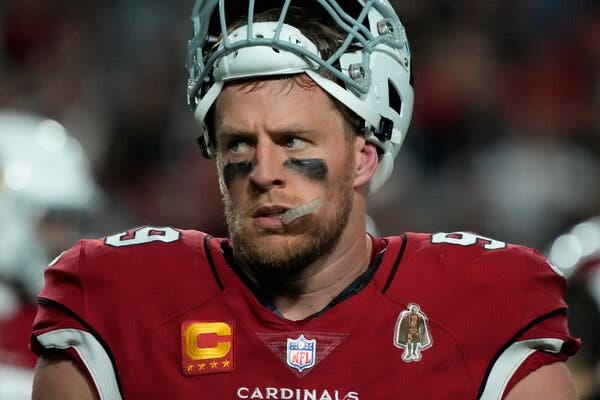 J.J. Watt, looking to his right while wearing a red Cardinals uniform with his white helmet pushed mostly off his head.