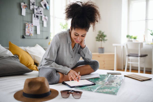 Young woman with tablet and map indoors at home, planning traveling trip. Happy young woman with tablet and map indoors at home, planning traveling trip. Travel planning stock pictures, royalty-free photos & images