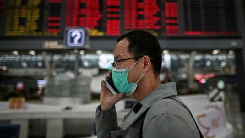 A man wearing a facemask speaks on a mobile phone at Shanghai Pudong international airport