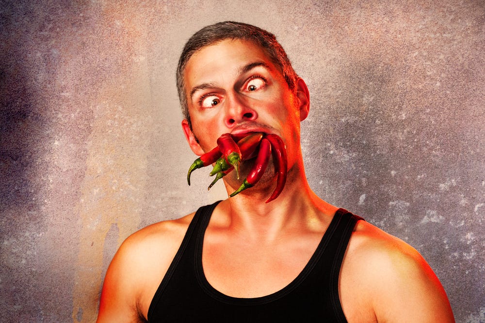 ridiculous expression of a man with lots of hot chillies in his mouth