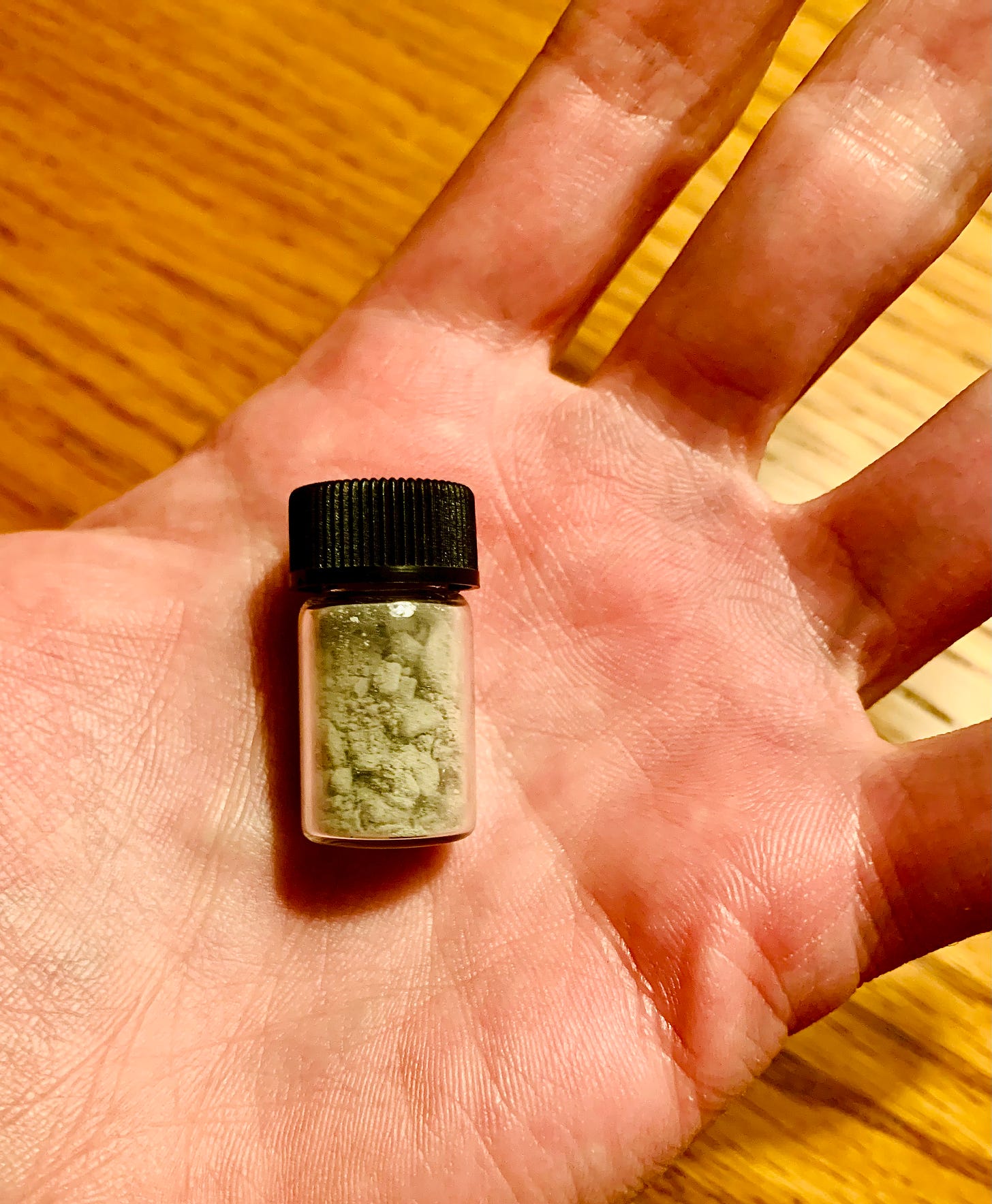 A small jar of grey dust in an open palm..