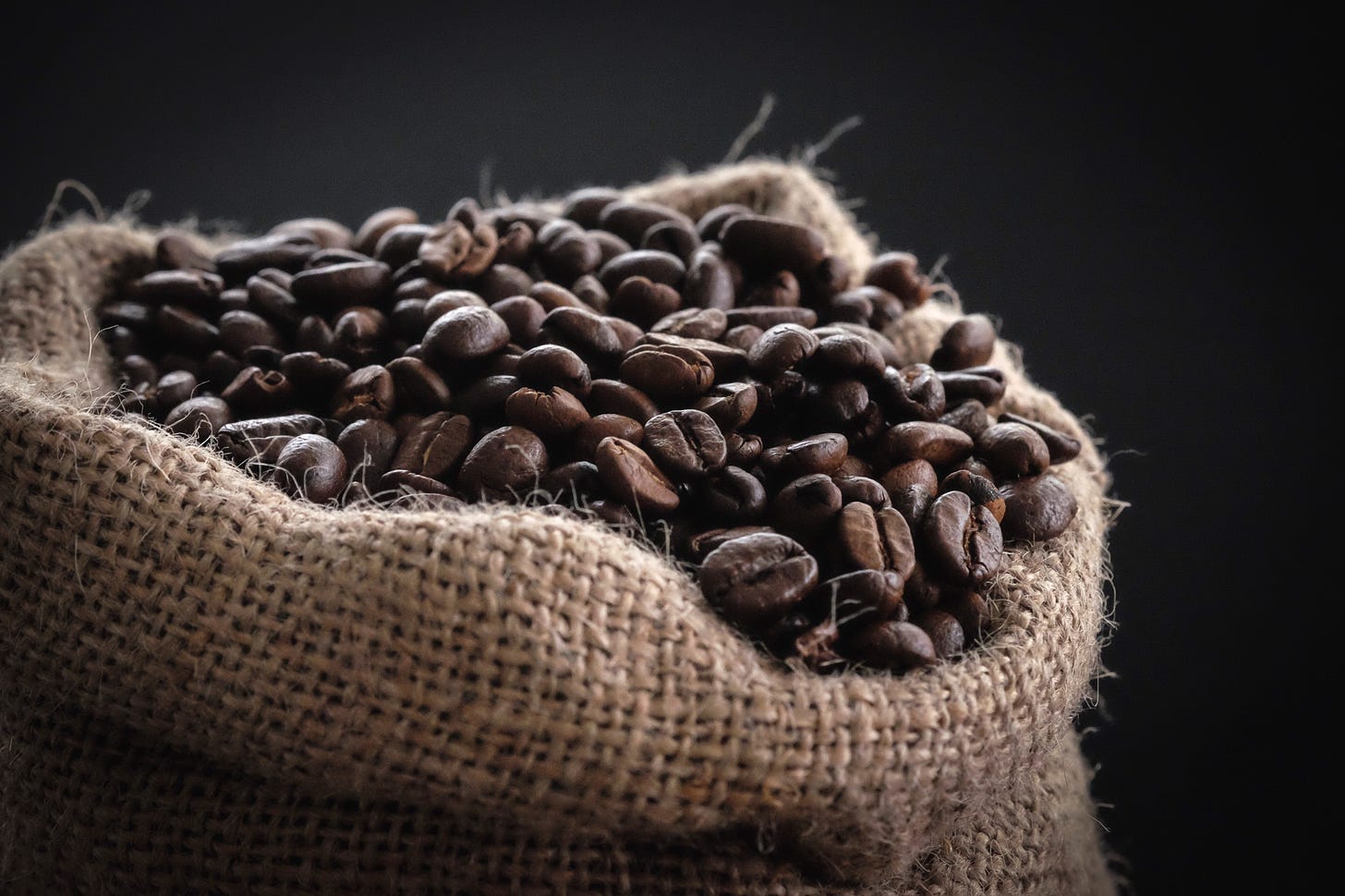 Image of roasted coffee beans in a small burlap sack.