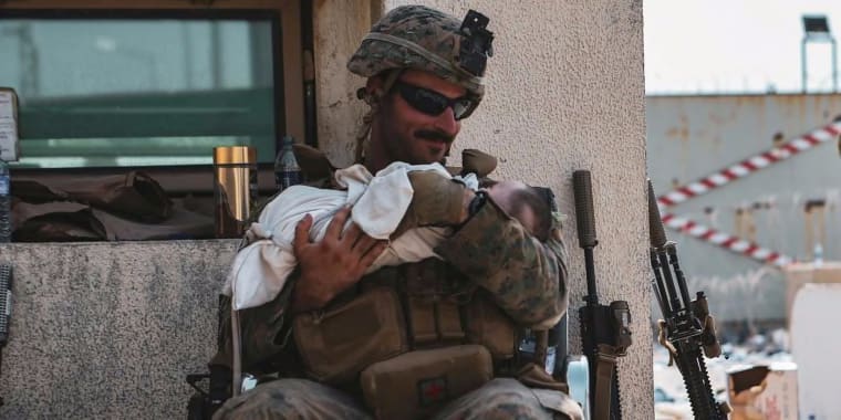 Image: A U.S. Marine assigned to the 24th Marine Expeditionary Unit (MEU) holds a baby during an evacuation at Hamid Karzai International Airport, Kabul