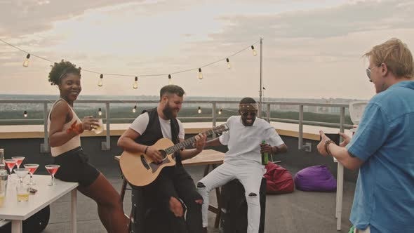Man playing acoustic guitar at a rooftop party