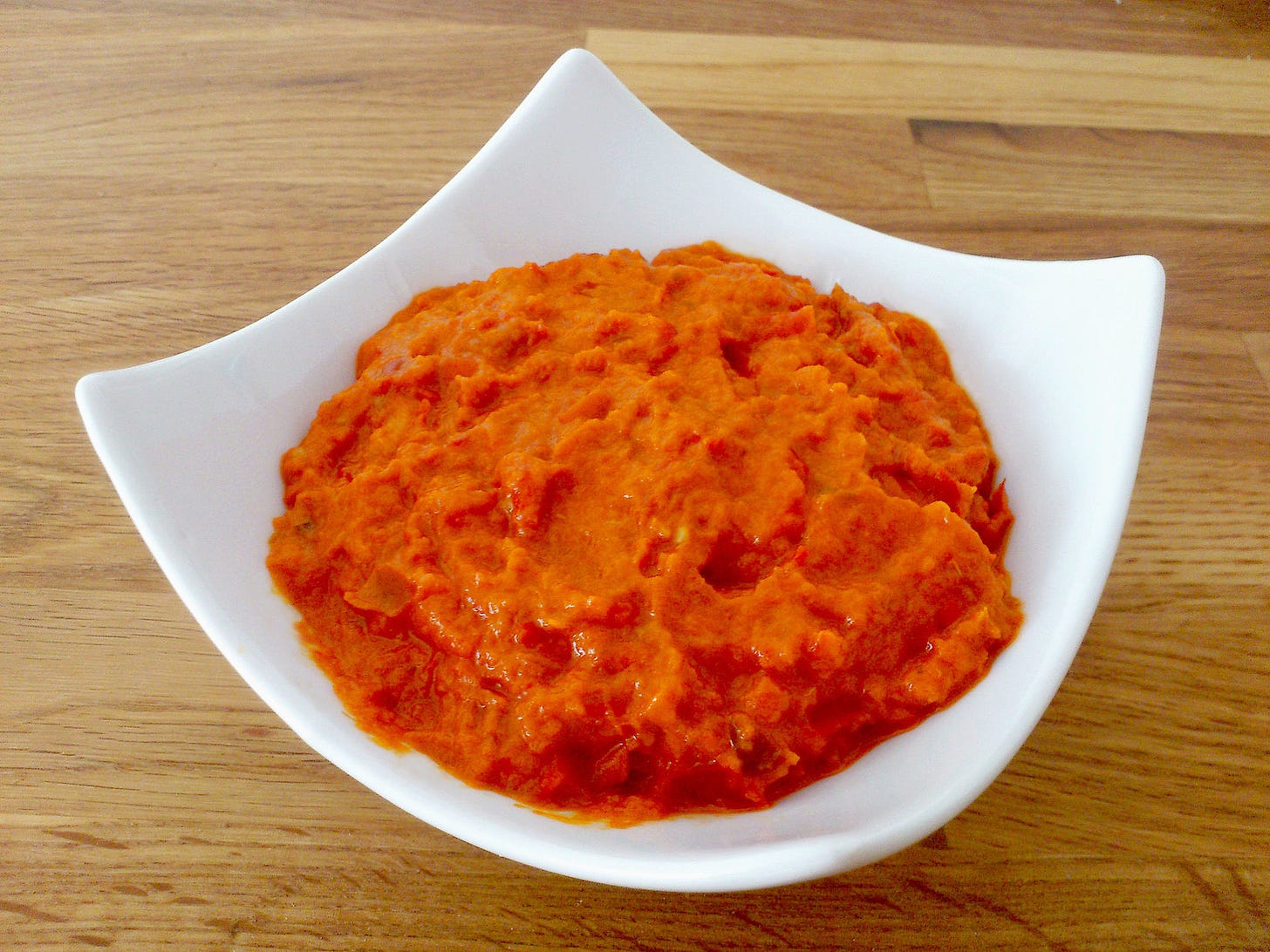 A white dish holding a serving of creamy ajvar. 