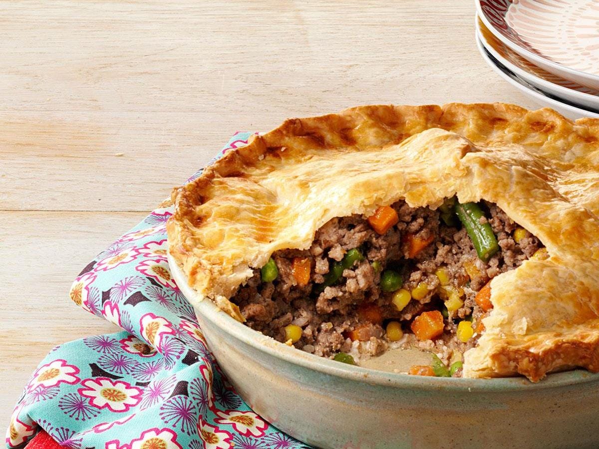 A tourtiere pie with a slice cut out so filling is exposed.
