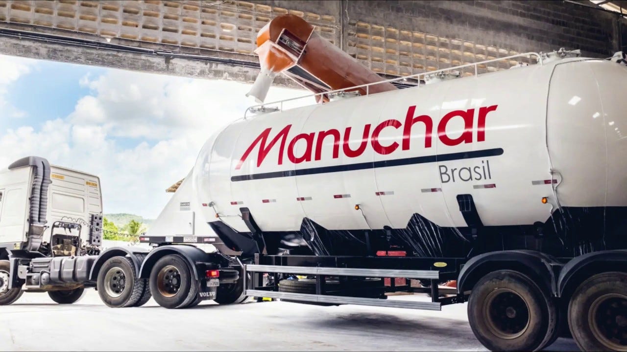 Caminhão de carga química com logo “Manuchar Brasil” em galpão.