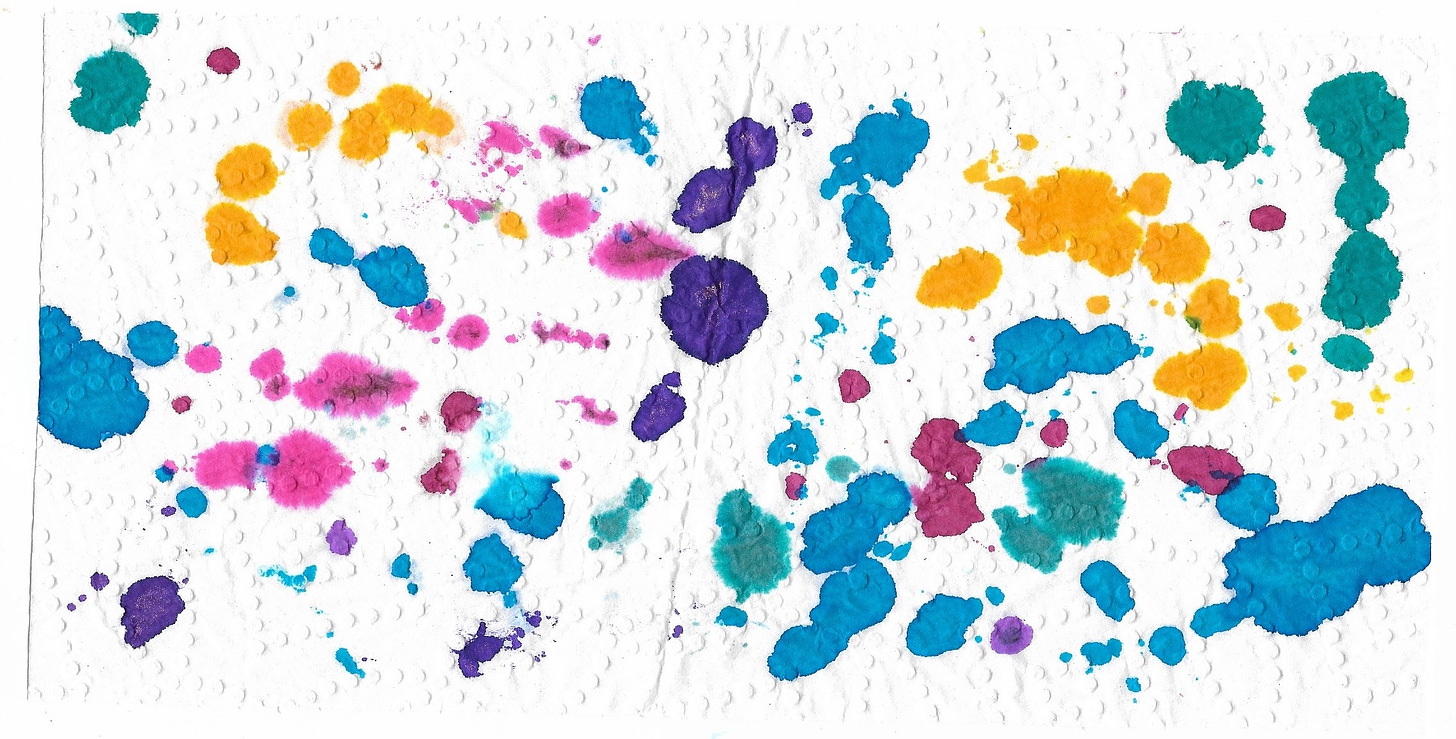 a rectangular piece of white paper towel with textured dots. it's splattered with ink in various colors: golden yellow, teal blue, purples, pinks