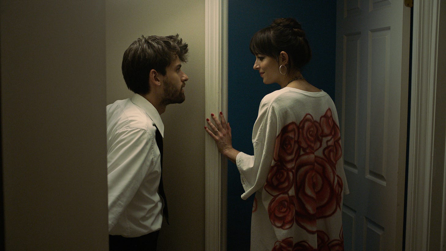 A still of Dakota Johnson and Cooper Raiff in a still from Cha Cha Real Smooth standing in a doorway