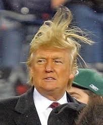 Trump’s hair flies in the wind as he tries to loosen his tie
