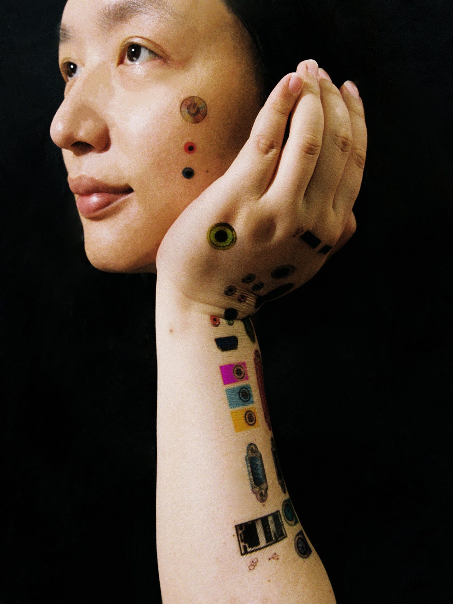 Audrey Tang with temporary tattoos of computer ports and power buttons on her face arm and hands