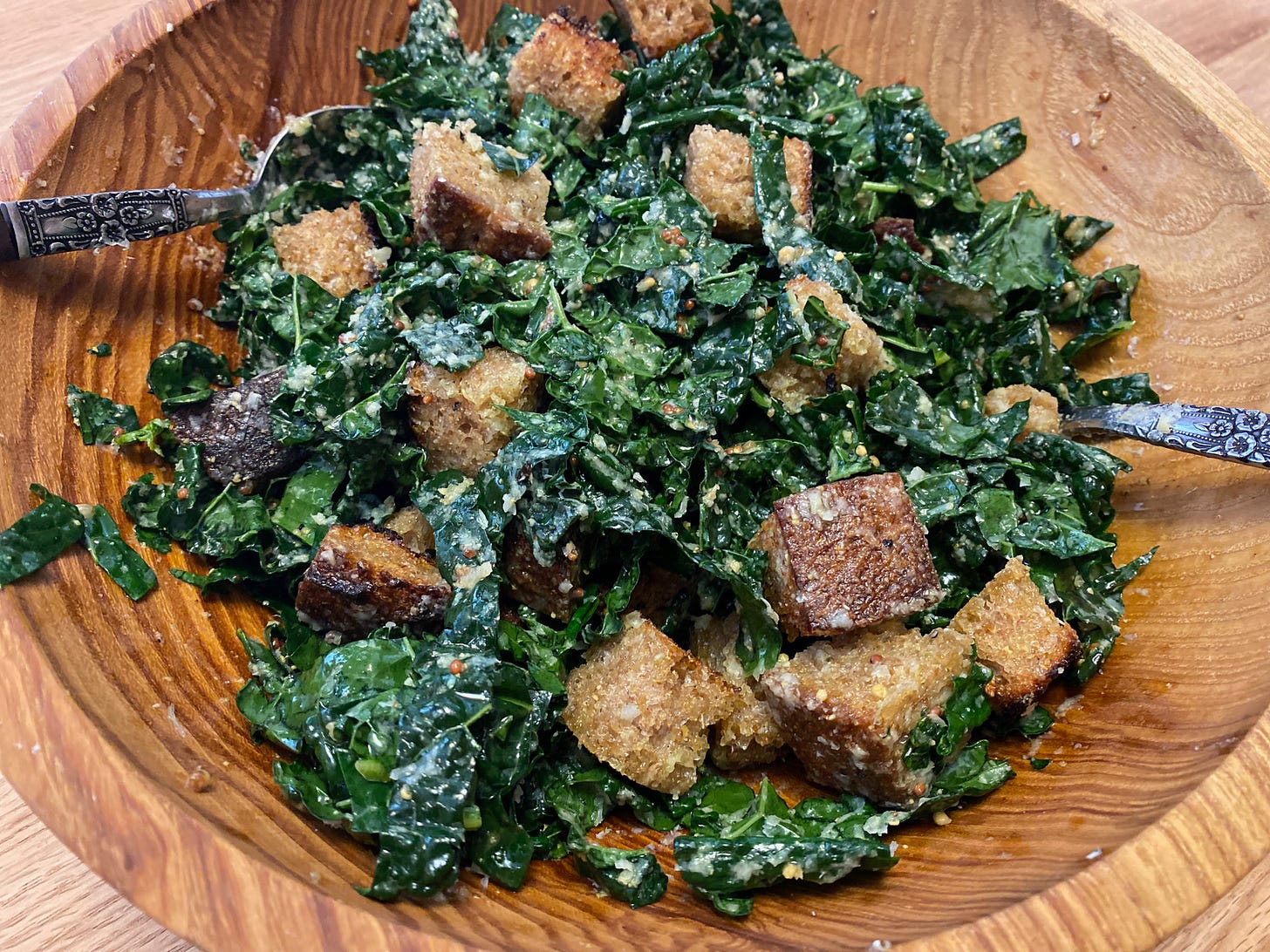 Closeup of a raw kale salad in a wooden bowl.