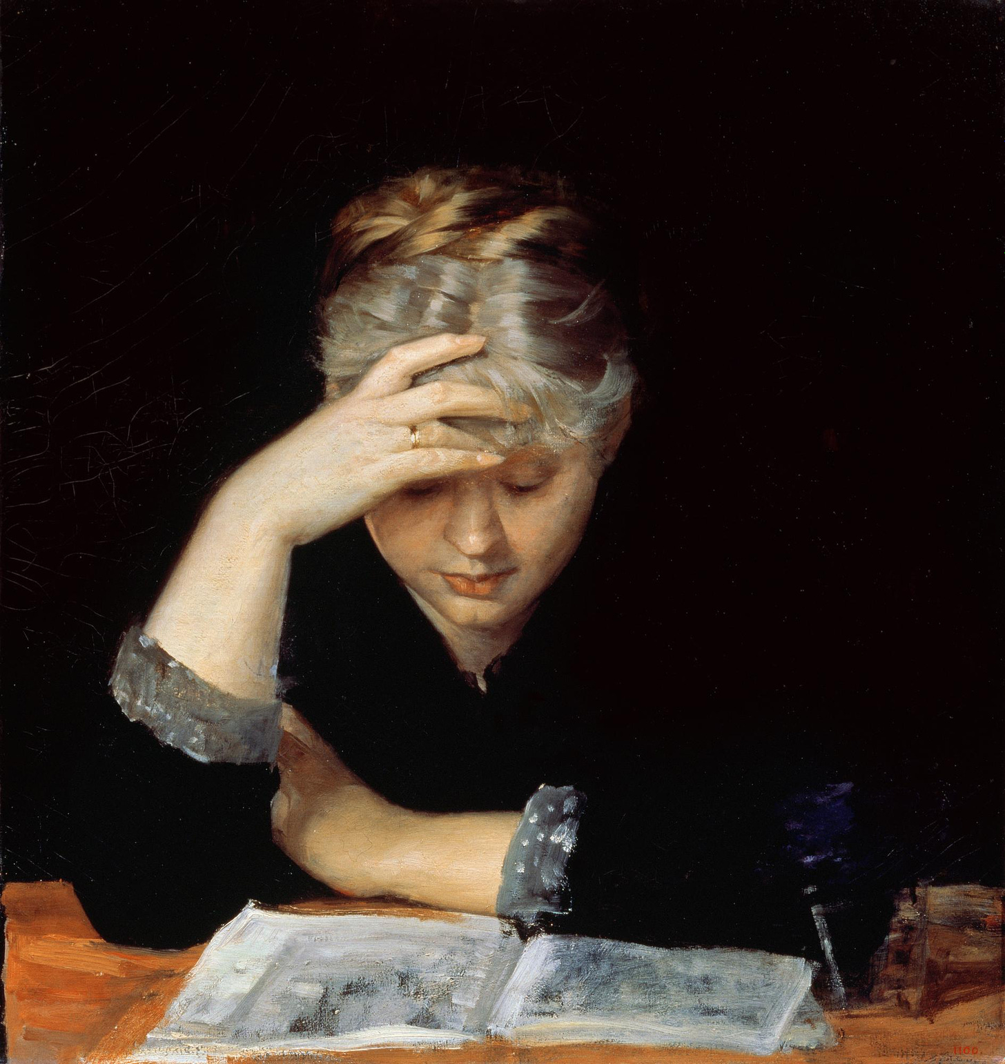 A woman bends over an open book, absorbed.