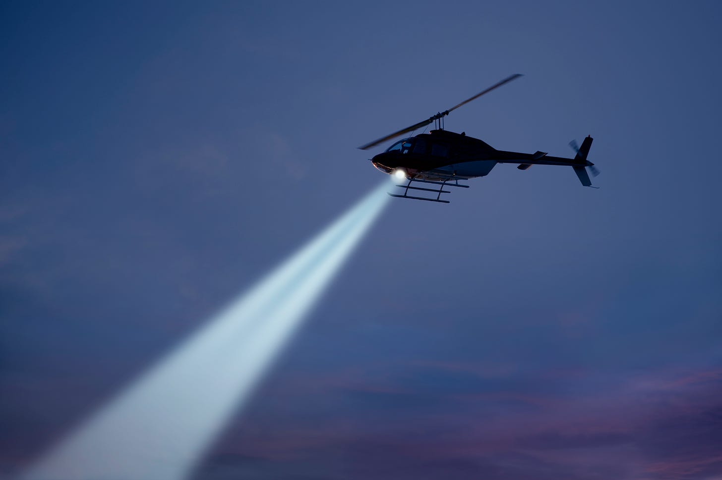 Helicopter with searchlight pointing  down at an angle to the left
