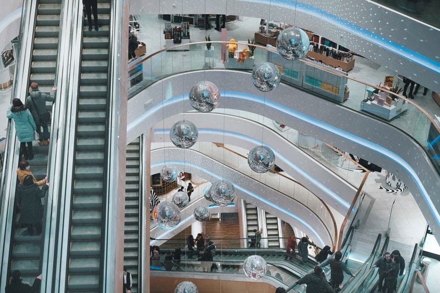 bird's eye view of escalators in a mall with disco balls hanging in it