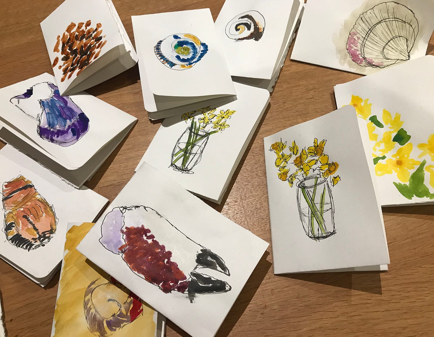 Photo of 11 small white cards with watercolour paintings of daffodils, shells and a crab claw
