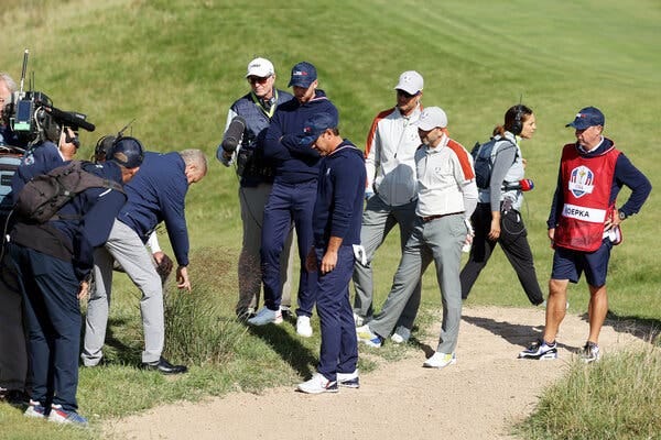 Brooks Koepka, center, argued with rules officials on Saturday morning after his tee shot on the 15th hole landed near a drain.