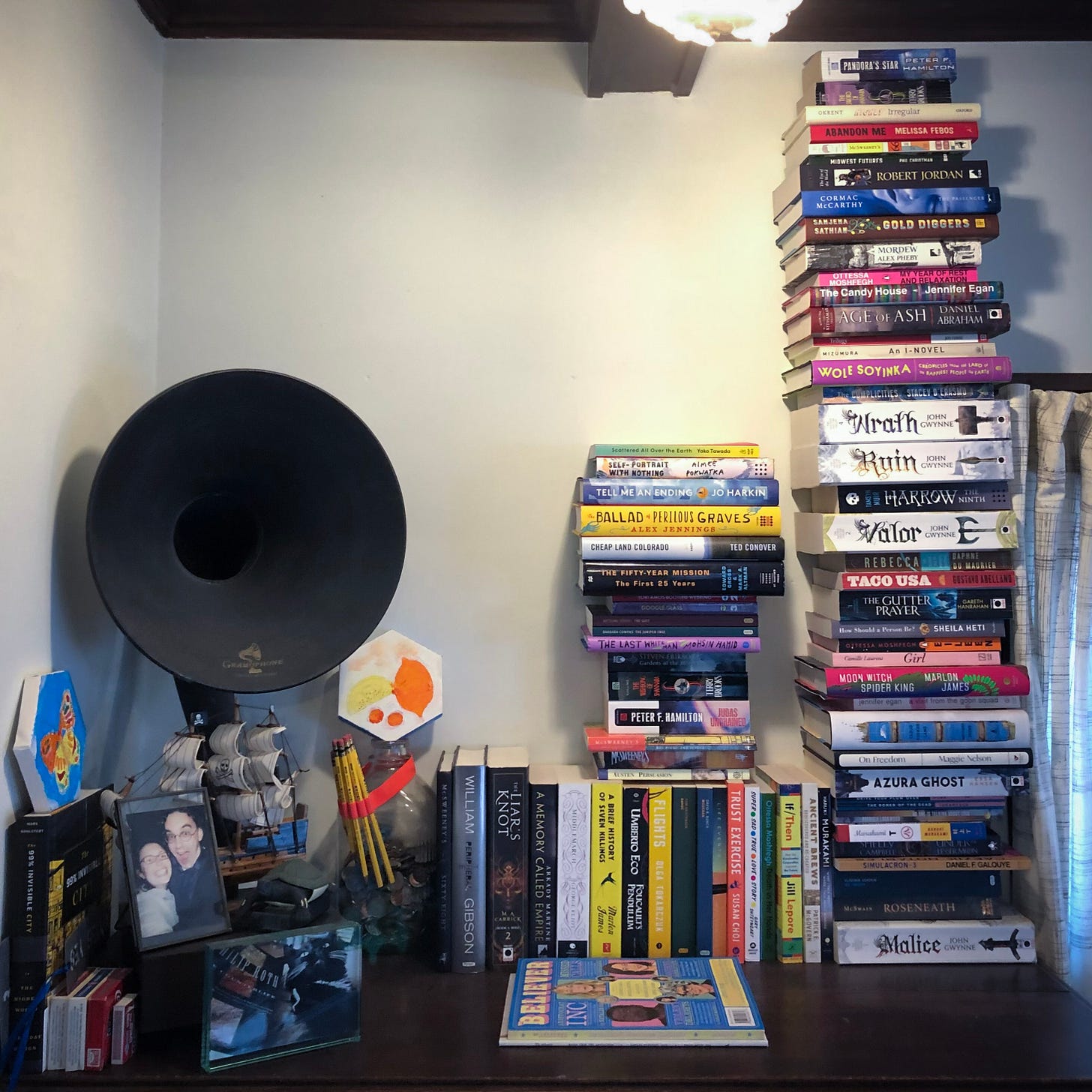 A large pile of about 43 books next to smaller piles of books.