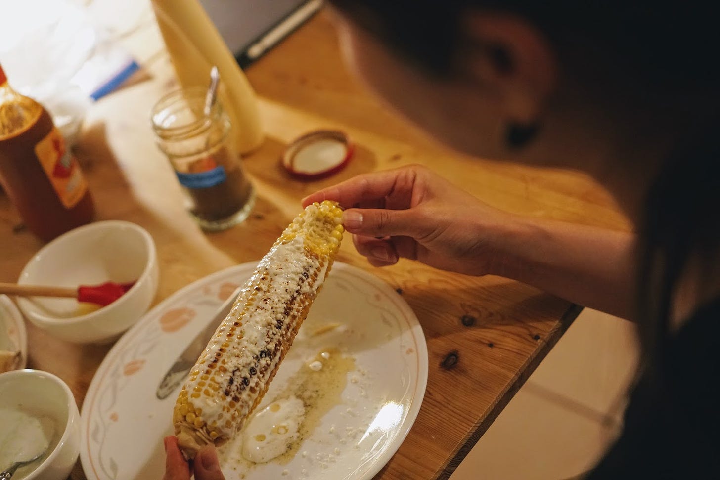 Grilled corn topped with butter and cheese in Yoko's hands