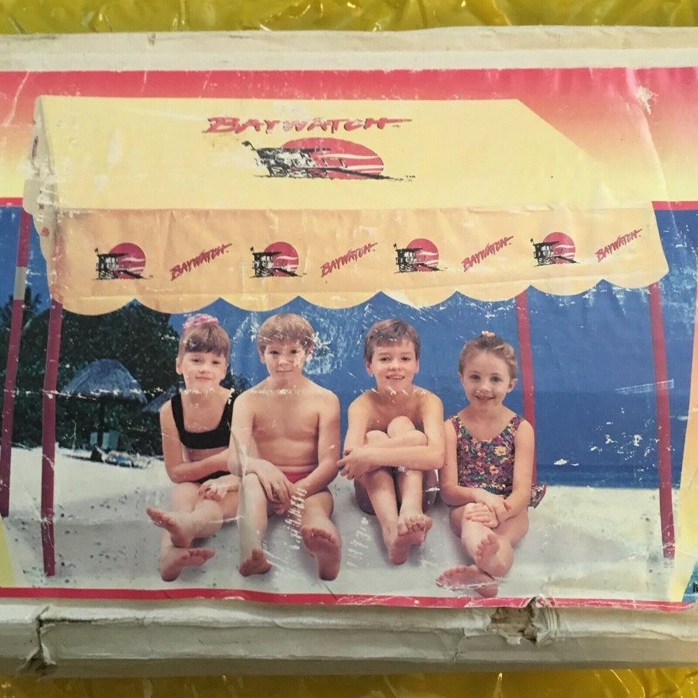 A photo from the packaging of a Baywatch gazebo tent that shows 4 children in swimsuits under said tent.