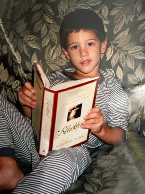 Image of the author's four year old son holding a copy of her first book, Blackbird 