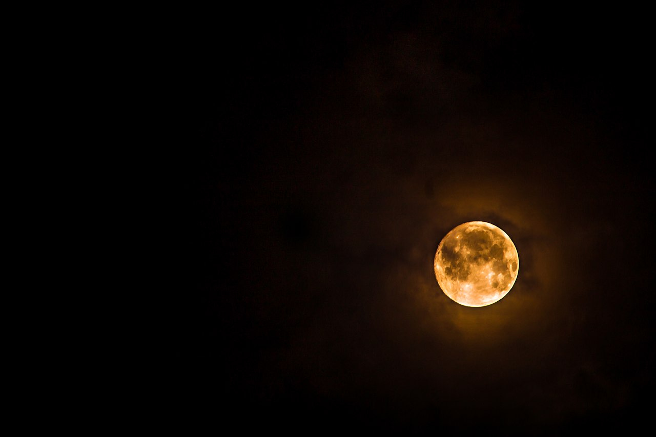 A yellow moon against a dark night sky