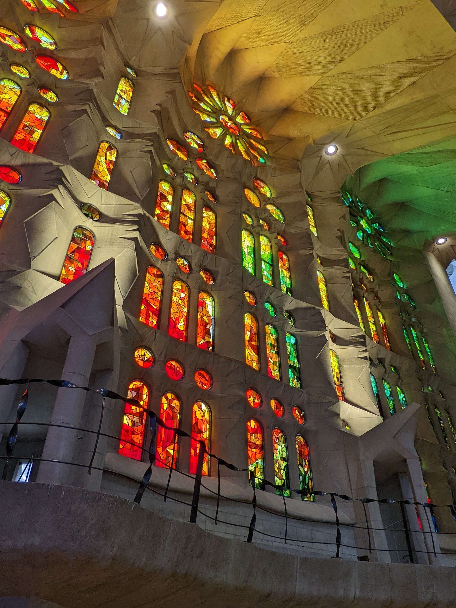 An interior shot of the stained glass of the Sagrada Familia. Orange and yellow and red glass lights up so brightly that the white stone underneath seems to glow.
